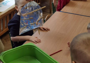 Koleje doświadczenie z wodą- dzieci obserwują wbijanie ołówków do woreczka z wodą