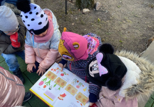Dzieci przeglądają książkę w ogrodzie