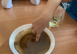 Dzieci sprawdzają, jak zachowa się pieprz kiedy dotkniemy go palcem umoczonym w płynie do naczyń