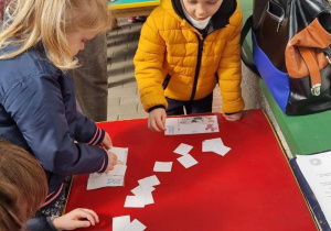Dzieci grają w zwierzęce bingo, muszą znaleźć odpowiednie zwierzątko i przykryć je kartonikiem