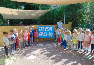 Grupa IV i V pozuje na tarasie, w tle napis Dzień Kropki wykonany przez dzieci z grupy V
