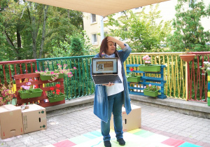 Pani Monika pokazuje dzieciom na komputerze przykładowe zdjęcia prac z recyklingu