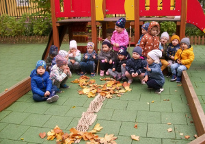 Wspólne zdjęcie dzieci z ułożonym drzewem w ogrodzie przedszkolnym