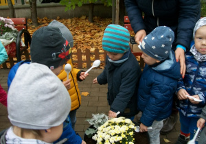 Dzieci obsypują ziemią posadzone kwiatki w doniczce